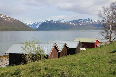 Houses at lakeshore by snow covered mountains against sky