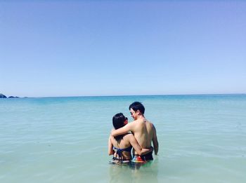Couple in sea against clear sky