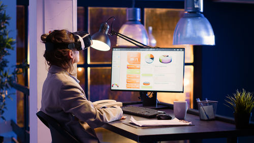 Rear view of woman using laptop at office