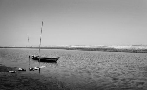 Sailboats moored in sea against clear sky