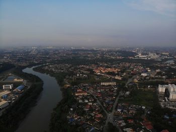 High angle view of illuminated city by river against sky