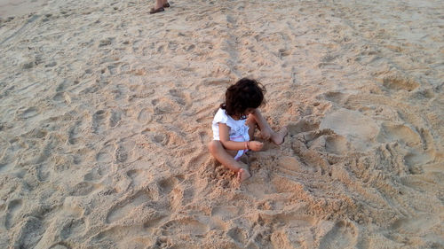 High angle view of girl playing with sand at beach