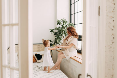 Happy mom and little daughter baby relax unwind and play in a cozy room in a cozy house