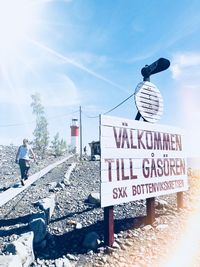 Information sign on road against sky