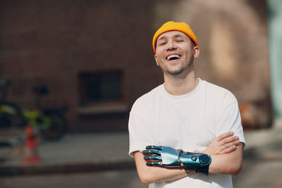 Young man wearing hat holding camera while standing outdoors