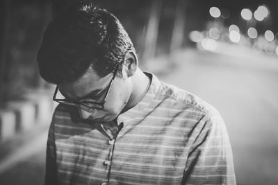 Young man in eyeglasses standing on street at night