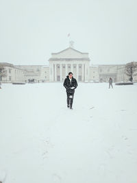 Man walking against buildings in city during winter