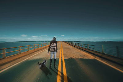 People on railing by sea against sky