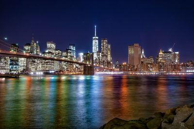 Brooklyn bridge over east river against illuminated manhattan at night