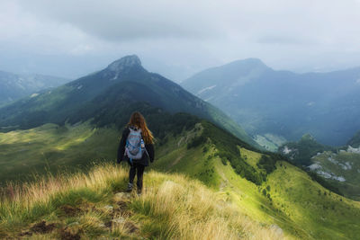 Rear view of woman standing on mountain against sky