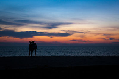 Silhouette man standing on beach against sky during sunset