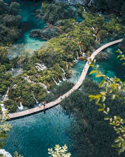 People walk across wooden path over lakes and waterfall at plitvice lakes national park.