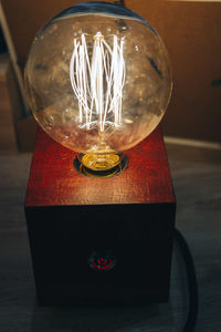 Close-up of illuminated light bulb on table