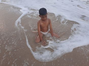 Full length of shirtless boy on beach