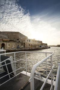 View of buildings by sea against cloudy sky