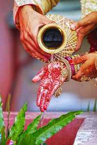 Cropped hand pouring water on bride tattooed during wedding ceremony