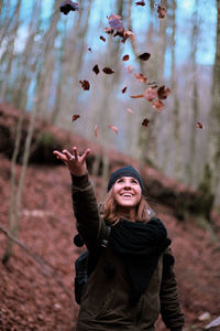 Portrait of young happy girl throws leaves in the air
