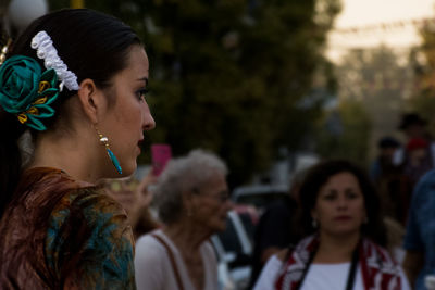 Side view of young woman wearing earring and hair accessory outdoors