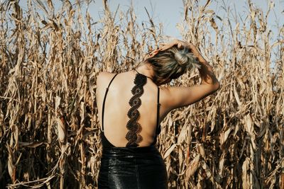 Rear view of woman standing against plants on agricultural field