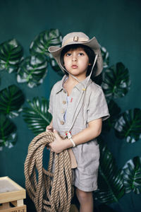 Boy child traveler in linen clothes holding a rope stands in the studio