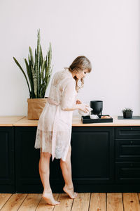 Full length of woman standing by potted plant at home