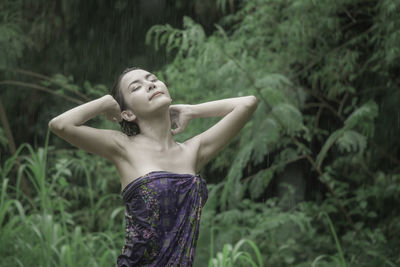 Woman with hand in hair standing outdoors during rainy season