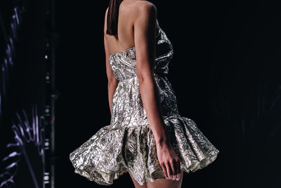 Creative silver dress, fashion details of interesting look on a female figure on a black background.
