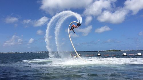 Man flyboarding over sea against sky