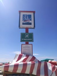 Low angle view of road sign against clear blue sky