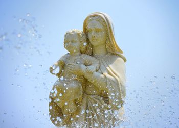 Close-up of statue of mary and jesus against blue background