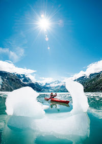 Woman kayaking in glacier bay national park with iceberg in foreground