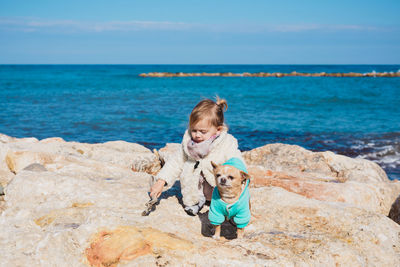 Portrait of boy on rock by sea against sky