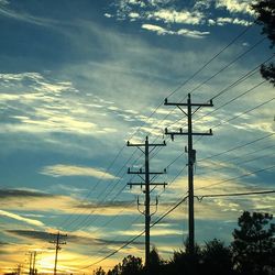 Low angle view of electricity pylon against cloudy sky