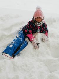 High angle view of girl sitting on snow covered field