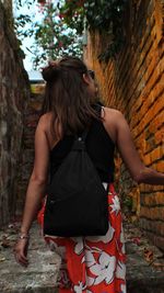 Rear view of young woman standing against trees