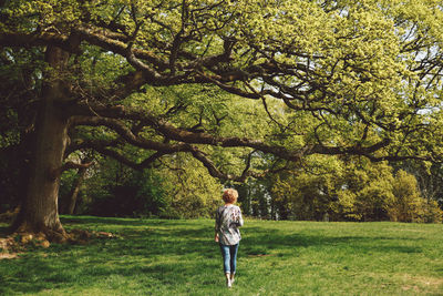 Rear view full length of woman walking by trees at park