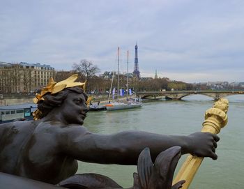 Statue on boat in city against sky