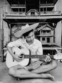 Man playing guitar against built structure