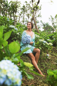 Young woman standing against plants