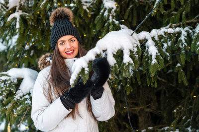 Portrait of smiling young woman standing against trees