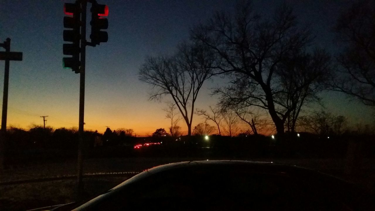 transportation, road, car, tree, sunset, land vehicle, street light, silhouette, mode of transport, illuminated, street, the way forward, sky, road marking, bare tree, night, dark, clear sky, on the move, dusk