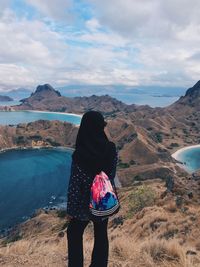 Rear view of woman standing on mountain against sky