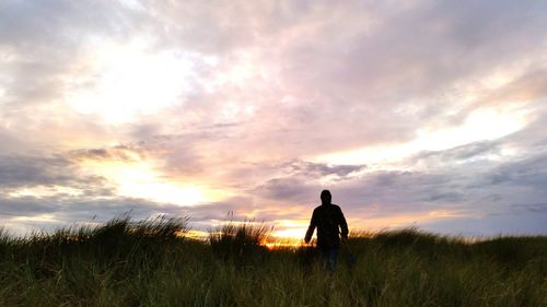 Rear view of silhouette man standing on field against sky