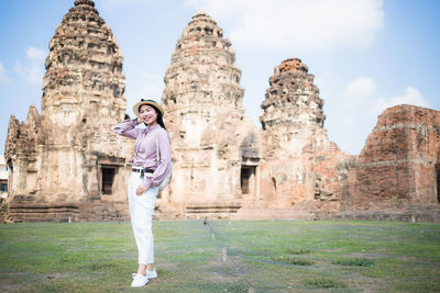 Smiling woman standing on land against old temples