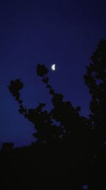 Low angle view of silhouette trees against blue sky