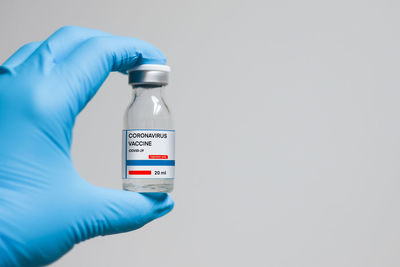 Close-up of hand holding bottle against white background