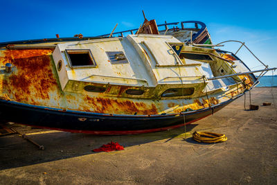 Abandoned urban boat moored at shore against sky