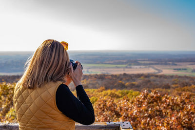 Side view of woman photographing landscape with camera