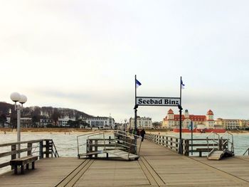 Information sign on pier against sky