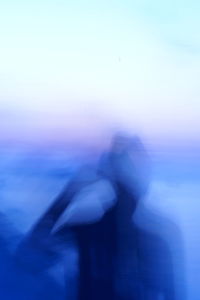 Blurred motion of silhouette woman standing against sky during sunset